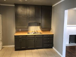 Tulsa house for rent - an empty kitchen with dark cabinets and a sink