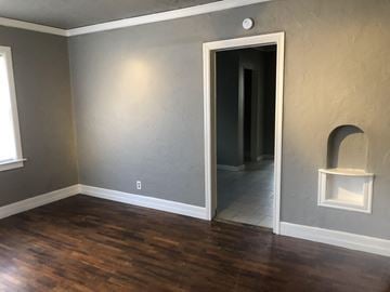 Tulsa house for rent - a living room with wooden floors and a door to a hallway
