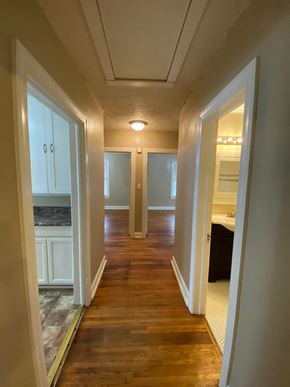 Tulsa house for rent - A long hallway with white doors and a wooden floor.