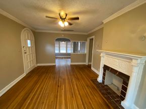 Tulsa house for rent - A room with a fireplace and a ceiling fan.