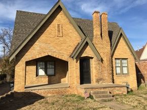 Tulsa house for rent - A small brick house with a black door and a small porch.