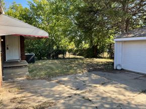 Tulsa house for rent - a backyard with a driveway and a garage and trees