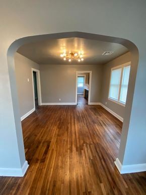 Tulsa house for rent - an empty living room with wooden floors and a ceiling fan