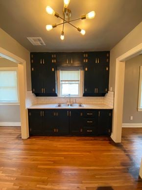 Tulsa house for rent - a kitchen with black cabinets and a sink and a window