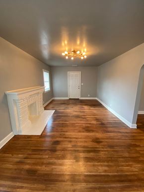 Tulsa house for rent - an empty living room with a fireplace and wooden floors