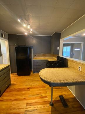 Tulsa house for rent - A kitchen with a black fridge and wooden floors.