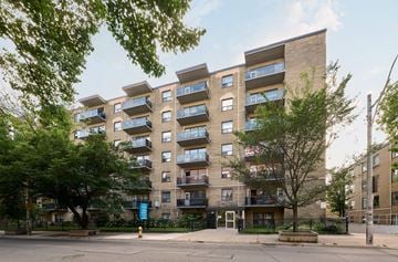 Toronto apartment for rent - A large apartment building with balconies and trees in front.