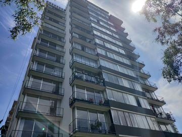 Vancouver apartment for rent - A tall building with balconies and windows is surrounded by trees.