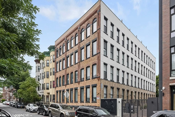 Brooklyn apartment for rent - a tall brick building with cars parked in front of it