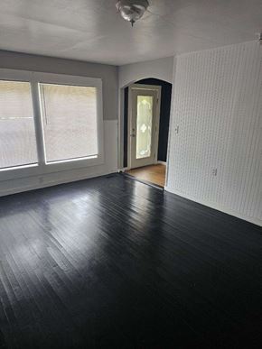 Monticello house for rent - an empty living room with wood flooring and large windows