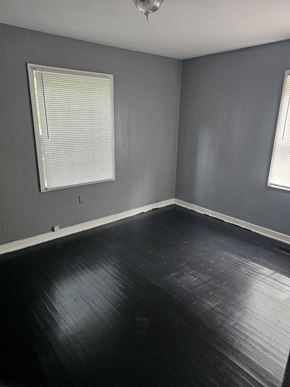 Monticello house for rent - an empty room with black wood floors and a window