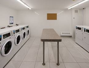 Scarborough apartment for rent - A laundromat with a table in the middle and washing machines on both sides.