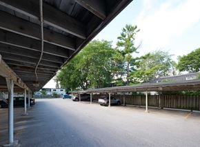 Oakville apartment for rent - A parking lot with cars parked under a wooden canopy.