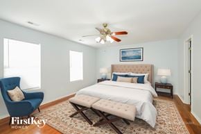 Charlotte house for rent - A bedroom with a bed, a chair, and a ceiling fan.