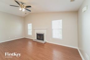 Charlotte house for rent - A spacious room with a fireplace and a ceiling fan.