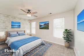 Charlotte house for rent - A bedroom with a bed, a ceiling fan, and a rug.