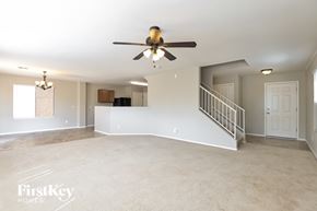 Tucson house for rent - A spacious room with a ceiling fan and a staircase.