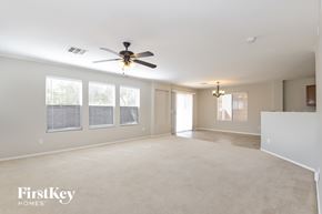 Tucson house for rent - A spacious room with a ceiling fan and windows.