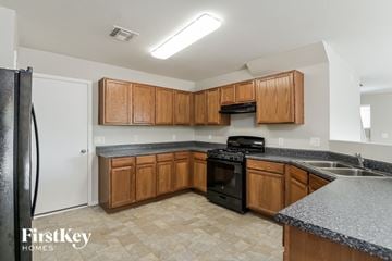 Tucson house for rent - A kitchen with wooden cabinets and a black stove top oven.