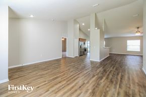 Palm Coast house for rent - A spacious room with wooden flooring and white walls, with a kitchen visible in the background.