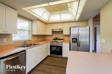 Cape Coral house for rent - a kitchen with white cabinets and stainless steel appliances