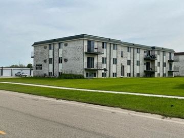 Moorhead apartment for rent - an old building with a green lawn next to a street