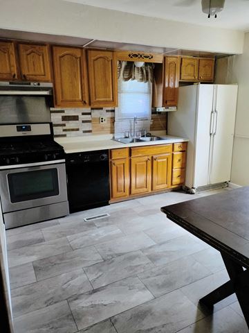 Hammond house for rent - a kitchen with wooden cabinets and stainless steel appliances