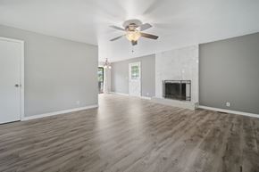 Jacksonville house for rent - A spacious room with a fireplace and a ceiling fan.