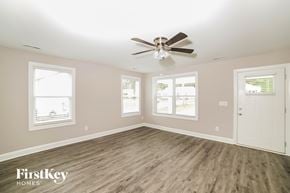 Winston Salem house for rent - A spacious room with a ceiling fan and wooden flooring.