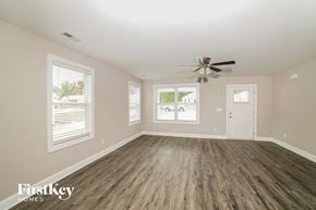 Winston Salem house for rent - A spacious room with a ceiling fan and wooden flooring.
