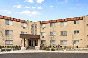 North Riverside apartment for rent - A large building with a brown roof and tan walls with a small tree in front.