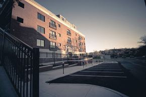 Rochester apartment for rent - A red brick building with a parking lot in front.
