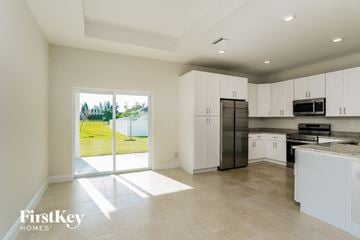 Cape Coral house for rent - a large kitchen with white cabinets and stainless steel appliances