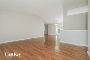 Maineville house for rent - A spacious room with wooden flooring and white walls, branded with "FirstKey Homes".