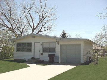 Boulder apartment for rent - A white house with a garage door and a tree in the front yard.
