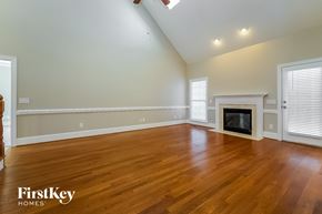 Whitsett house for rent - A spacious room with a fireplace and wooden floors.