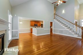 Whitsett house for rent - A spacious living room with wood floors and a staircase.