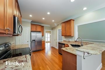 Whitsett house for rent - A kitchen with wooden cabinets and a granite countertop.