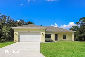 Port Charlotte house for rent - a yellow house with a lawn and a white garage door