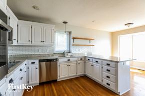 Raymore house for rent - a kitchen with white cabinets and stainless steel appliances