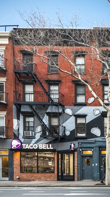 New York apartment for rent - A Taco Bell restaurant is located in a brick building with a black and white awning.