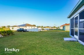 Cape Coral house for rent - A blue car is parked in a grassy yard.