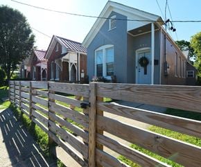 Louisville house for rent - A wooden fence in front of a grey house with a wreath on the door.