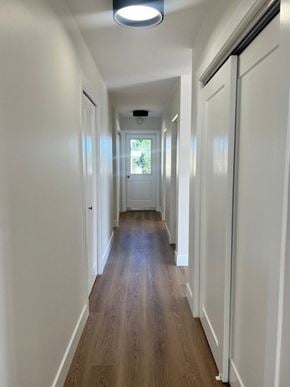 Nanaimo apartment for rent - A long hallway with white walls and wood floors.