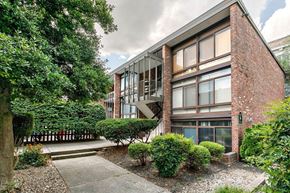 Louisville apartment for rent - A modern building with a red brick facade and large windows is surrounded by a well-manicured garden.