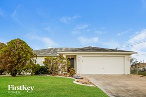 Cape Coral house for rent - the front of a white house with a lawn and a garage door