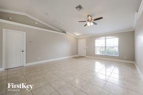 Cape Coral house for rent - an empty living room with a ceiling fan and a window
