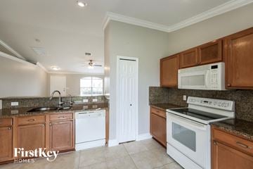 Cape Coral house for rent - a kitchen with white appliances and wooden cabinets