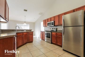 North Port house for rent - A kitchen with wooden cabinets and a stainless steel refrigerator.