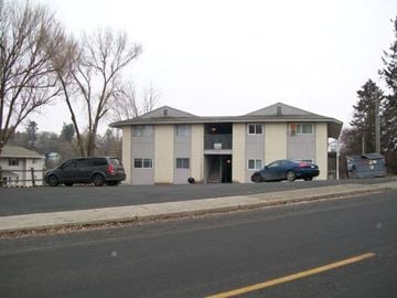 Pullman apartment for rent - A two-story building with a garage door is situated on a street with a parked car and a van.